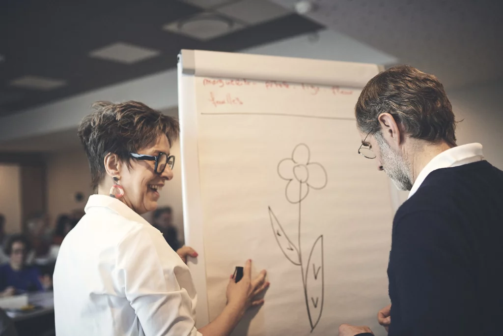 Delphine dessinant une fleur sur un paper board